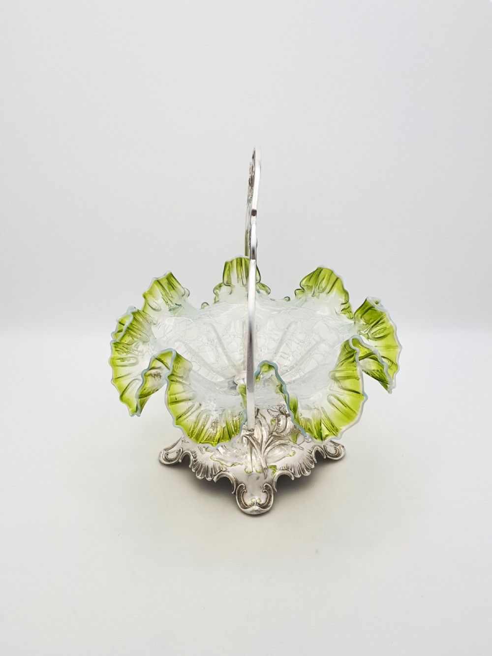 An Art Nouveau silver-plated centrepiece frame with an arched handle holding a frilled green-rimmed vaseline glass dish with a crackle texture. View VII