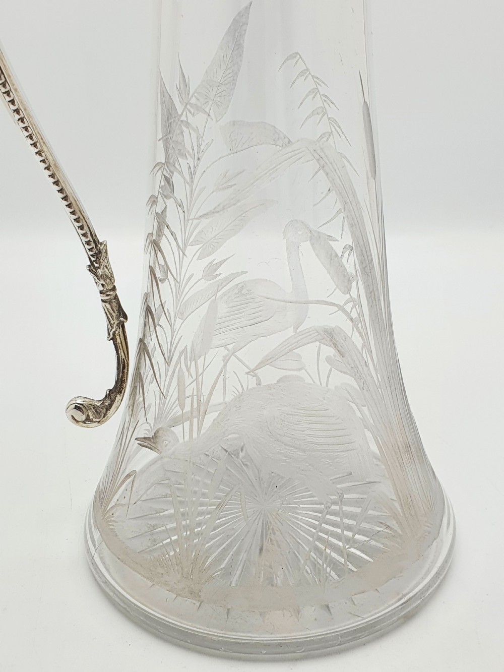 A Victorian etched clear glass claret jug featuring botanical engravings and a silver-plated handle, spout, and helmet finial. View III