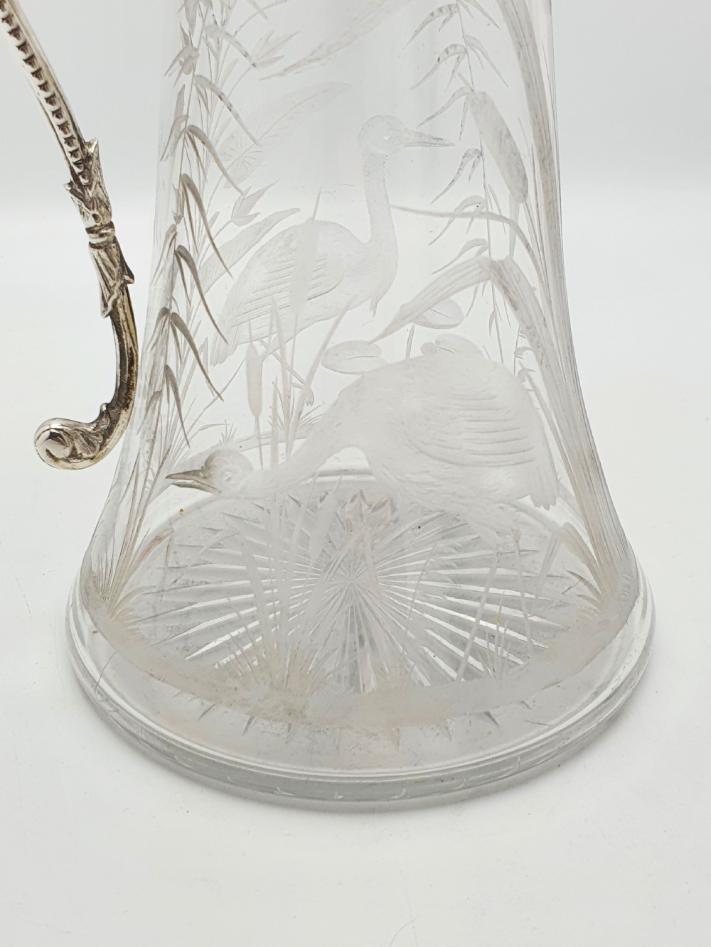 A Victorian etched clear glass claret jug featuring botanical engravings and a silver-plated handle, spout, and helmet finial. View IV