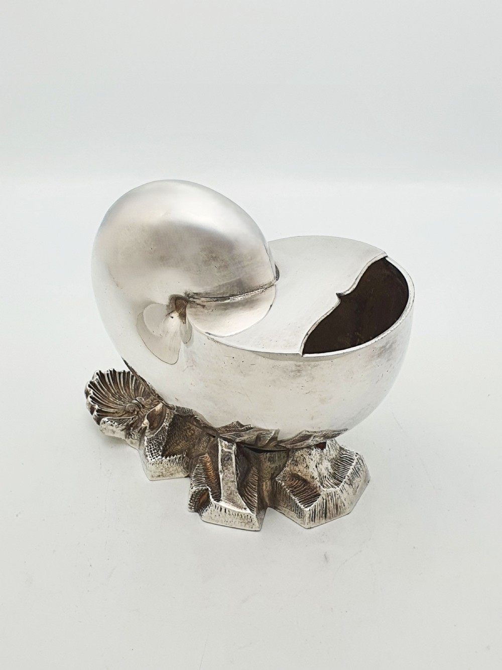 A Victorian silver-plated spoon warmer designed in the form of a nautilus shell mounted on a textured rocky base.