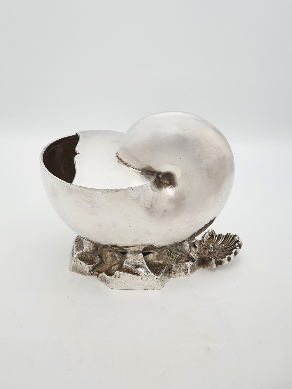 A Victorian silver-plated spoon warmer designed in the form of a nautilus shell mounted on a textured rocky base. View IV