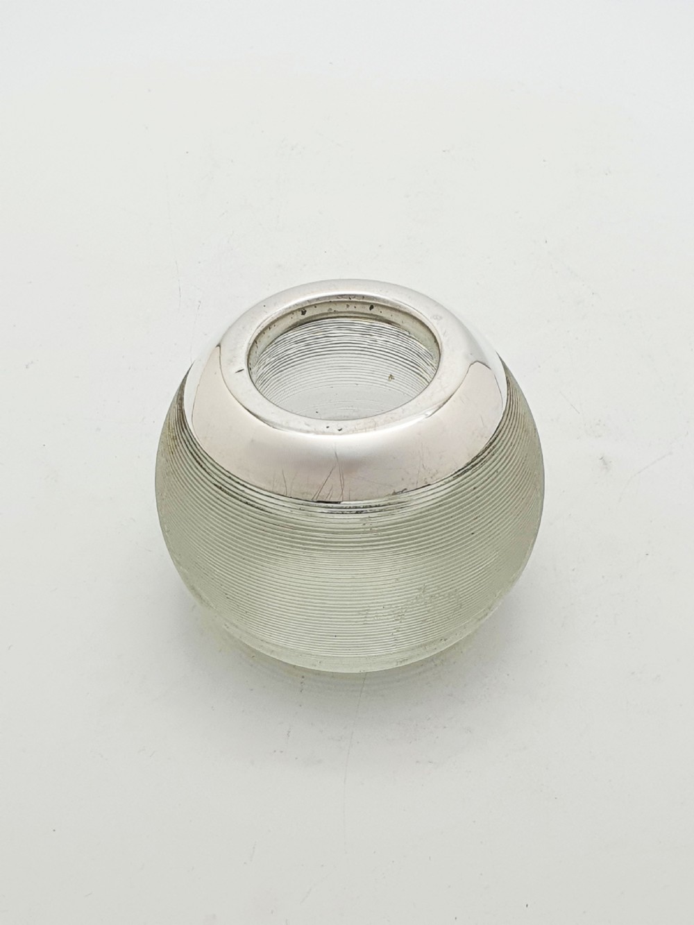 A spherical clear ribbed glass match striker featuring a hallmarked sterling silver collar around the top rim. View IV