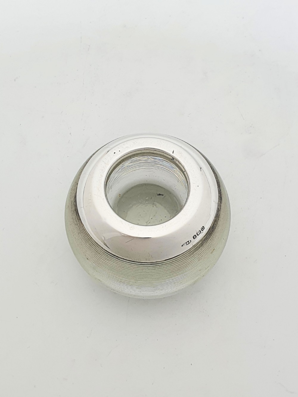 A spherical clear ribbed glass match striker featuring a hallmarked sterling silver collar around the top rim. View V