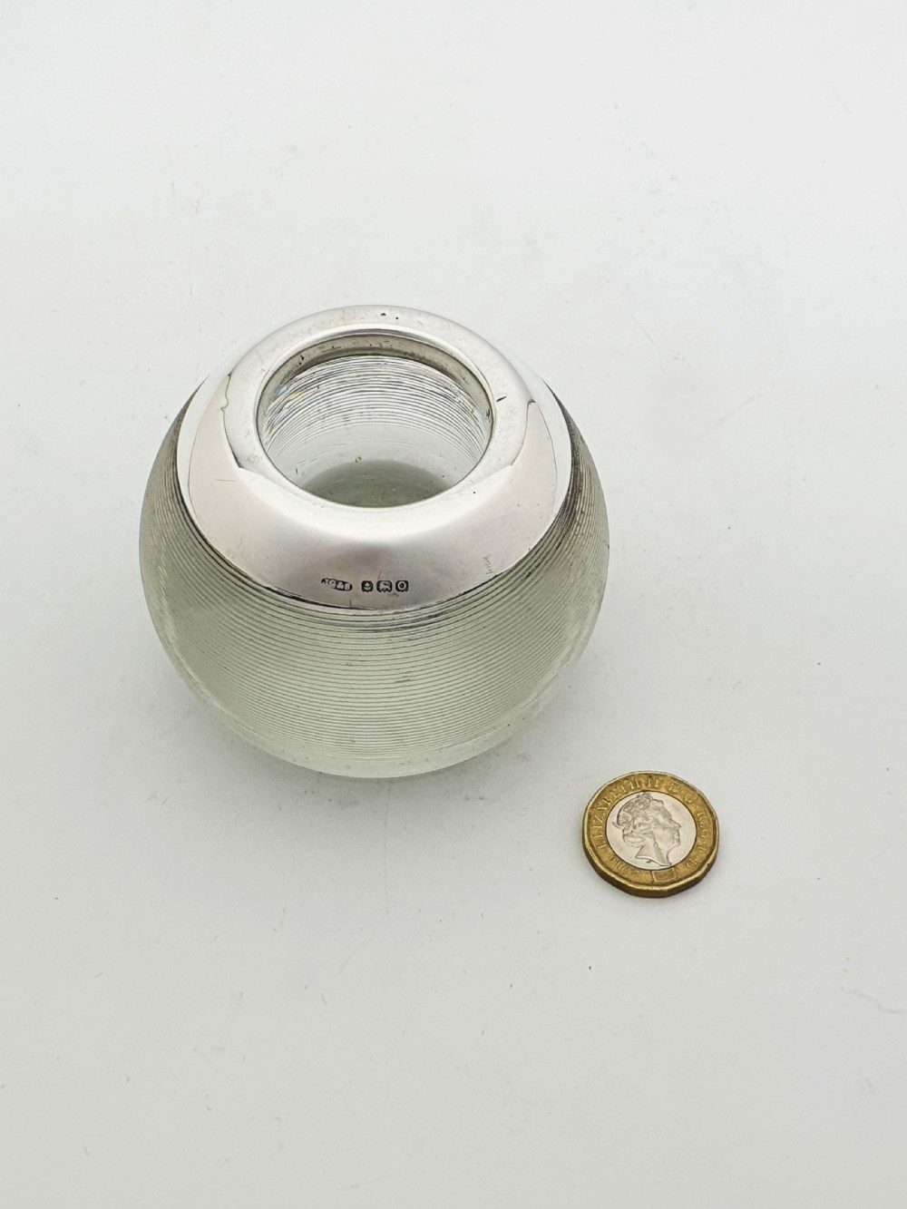 A spherical clear ribbed glass match striker featuring a hallmarked sterling silver collar around the top rim. View VI