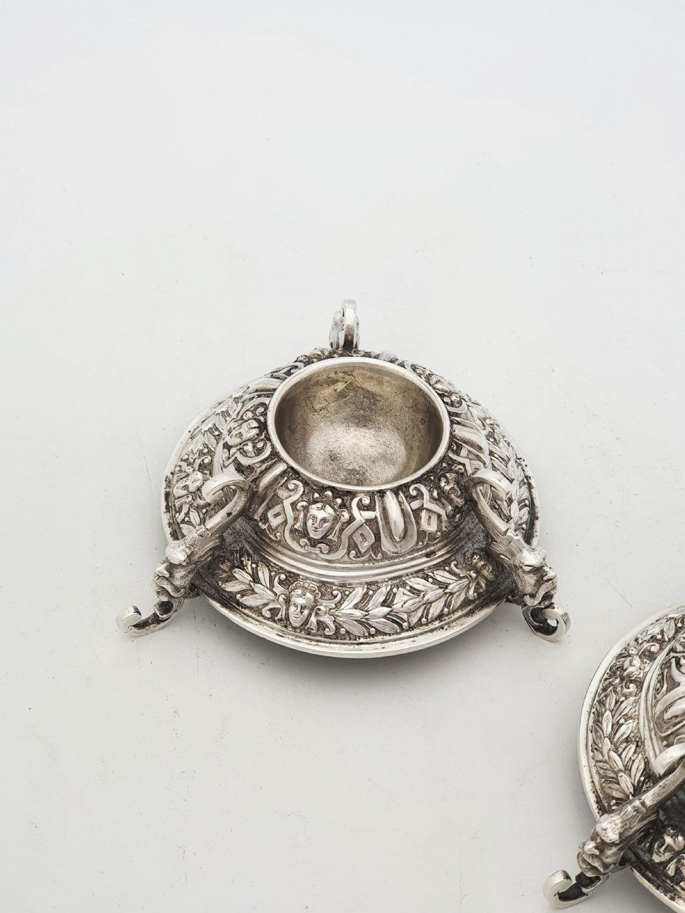 A pair of Victorian sterling silver salt cellars decorated with chased classical masks, foliate wreaths, and tripod feet. View III