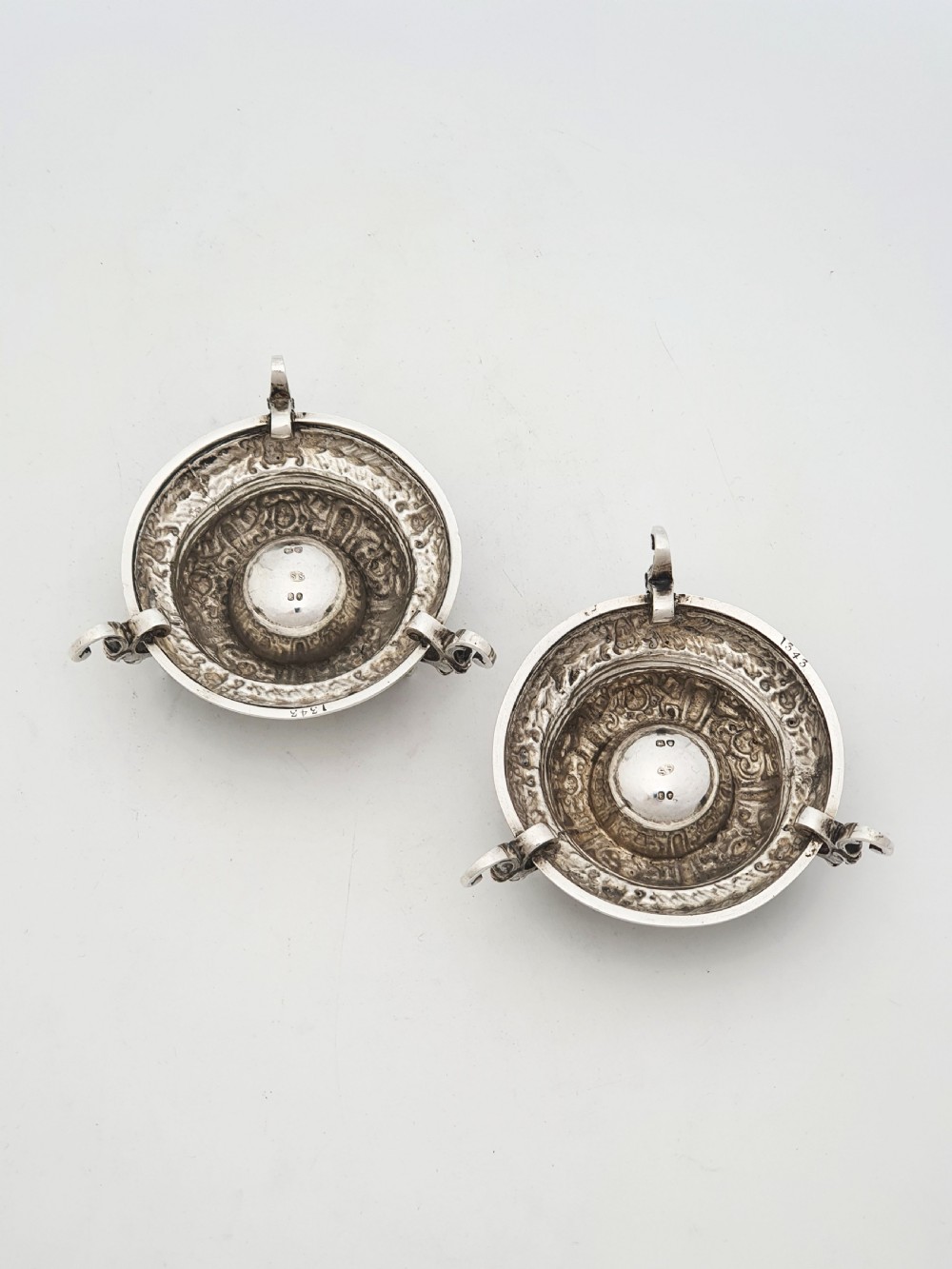 A pair of Victorian sterling silver salt cellars decorated with chased classical masks, foliate wreaths, and tripod feet. View VI