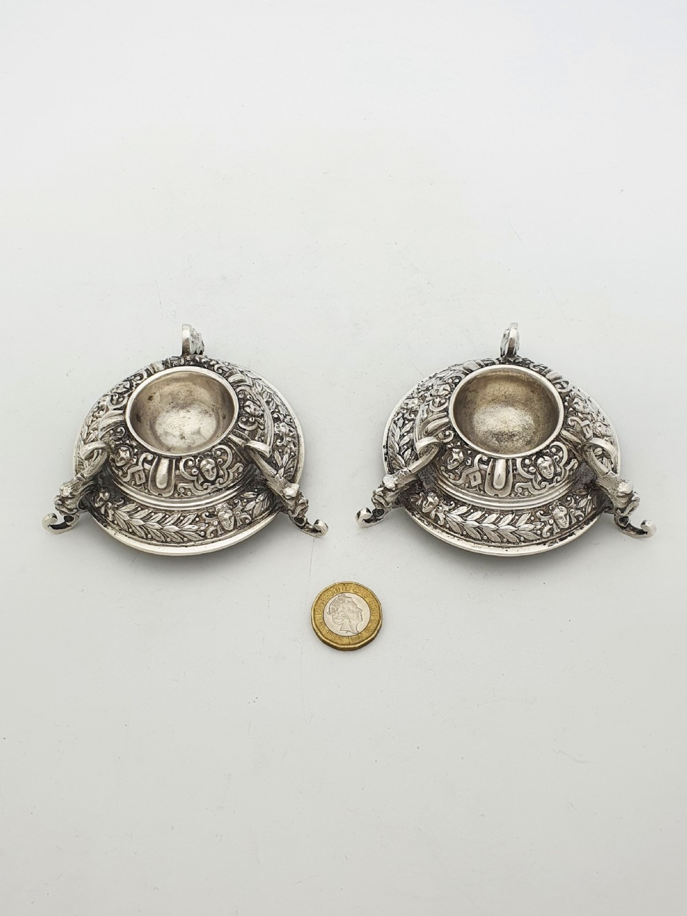 A pair of Victorian sterling silver salt cellars decorated with chased classical masks, foliate wreaths, and tripod feet. View XI