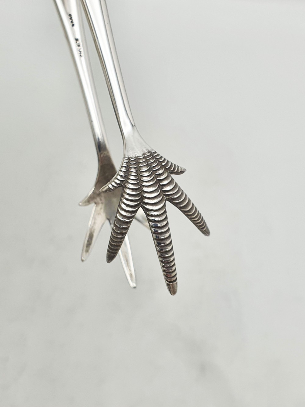 A pair of silver-plated Art Deco ice tongs featuring bird claw grippers and a top-mounted ice pick hammer head. View VII