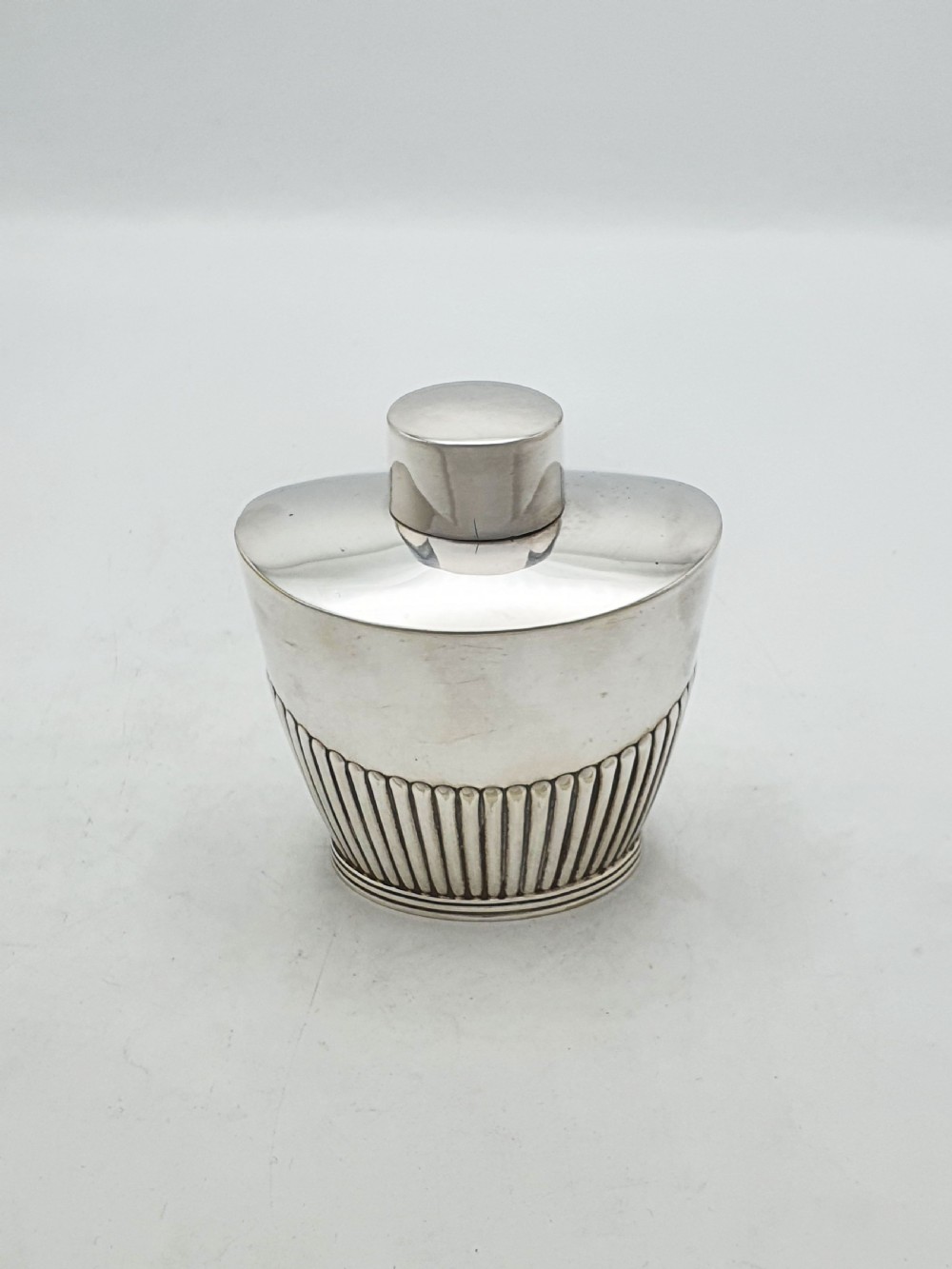 An Edwardian silver-plated tea canister featuring fluted body decoration and a fitted push-on lid.