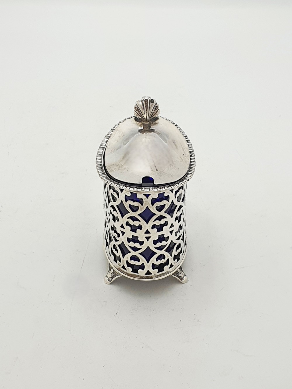 A Victorian sterling silver mustard pot with openwork lattice piercing, a hinged lid, a scroll handle, and a removable cobalt blue glass liner. View III