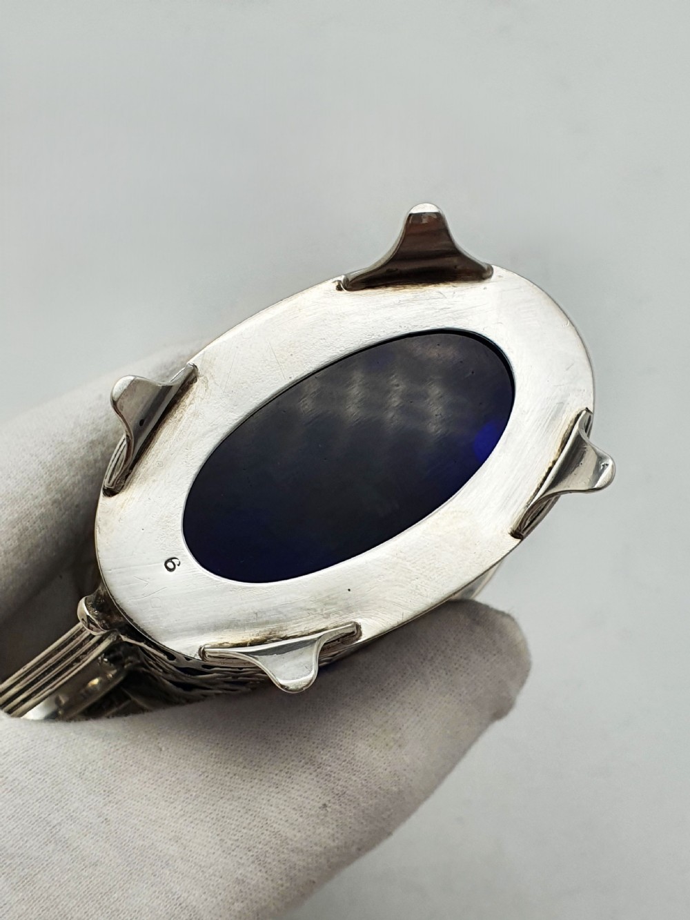 A Victorian sterling silver mustard pot with openwork lattice piercing, a hinged lid, a scroll handle, and a removable cobalt blue glass liner. View IX