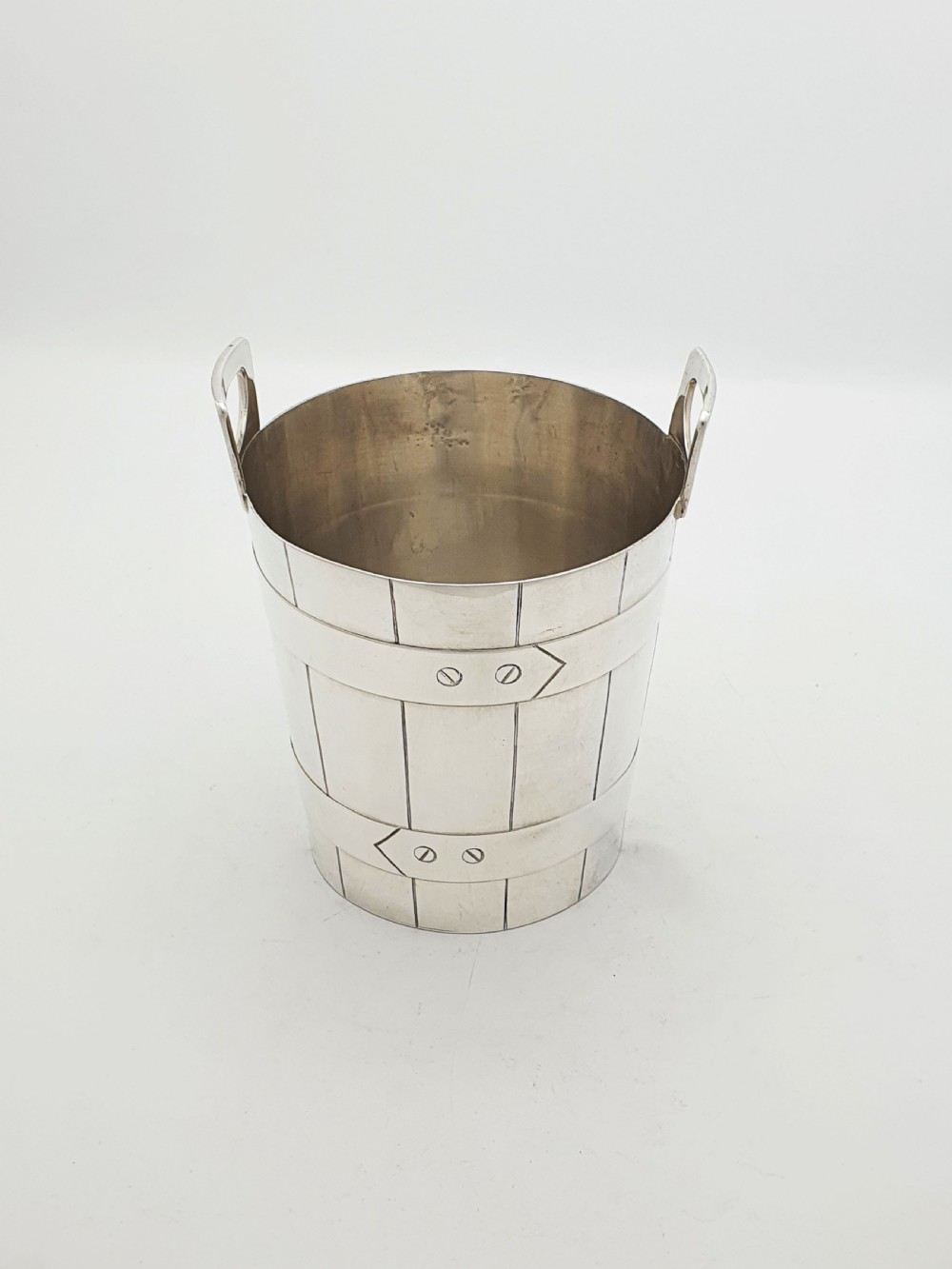 An Edwardian silver-plated ice bucket shaped like a wooden barrel with integrated handles alongside matching claw-foot ice tongs. View III