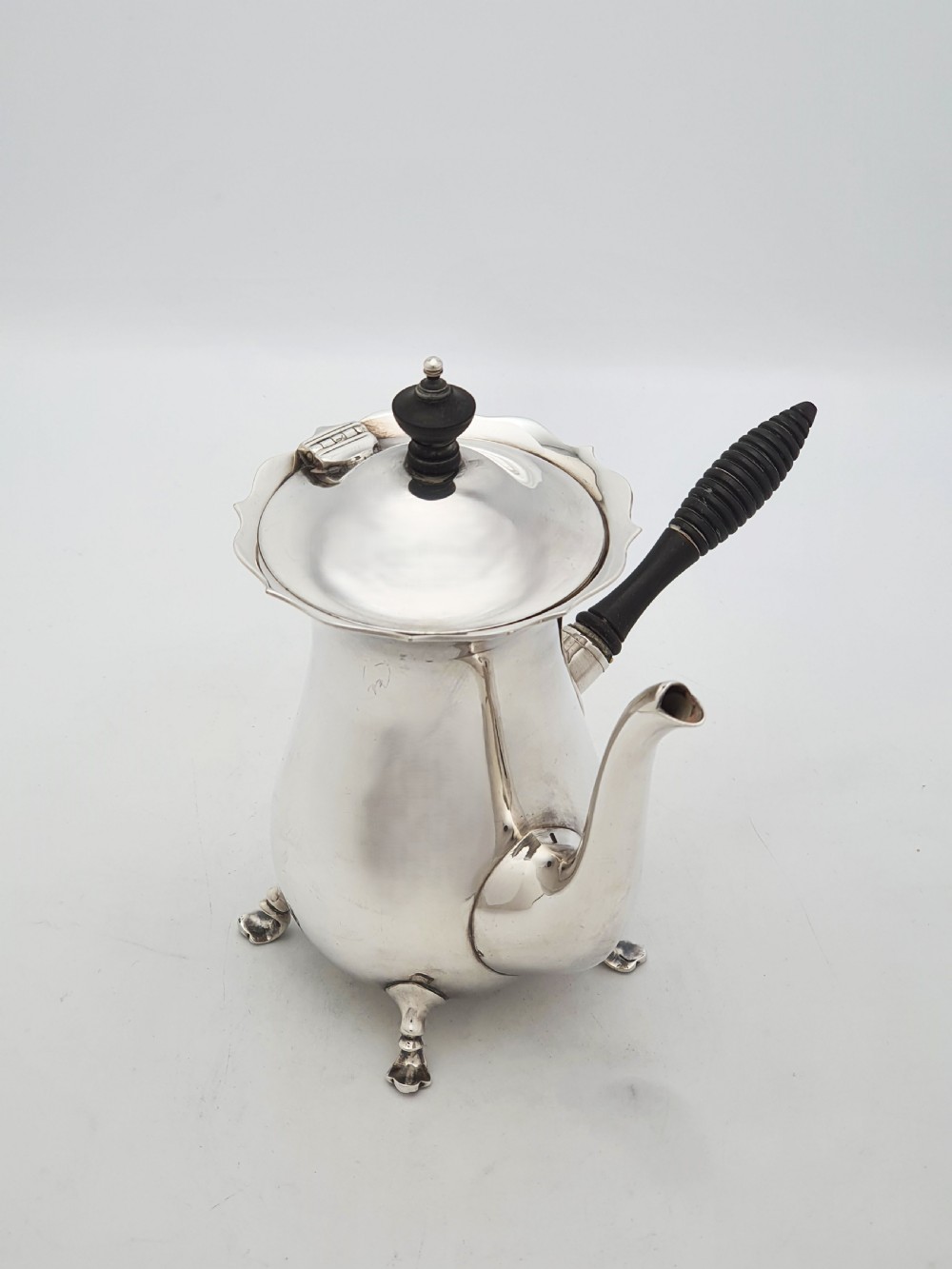 A pair of Edwardian silver cafe au lait pots featuring ribbed wooden side handles, scalloped hinged lids, and carved cabriole feet. View V