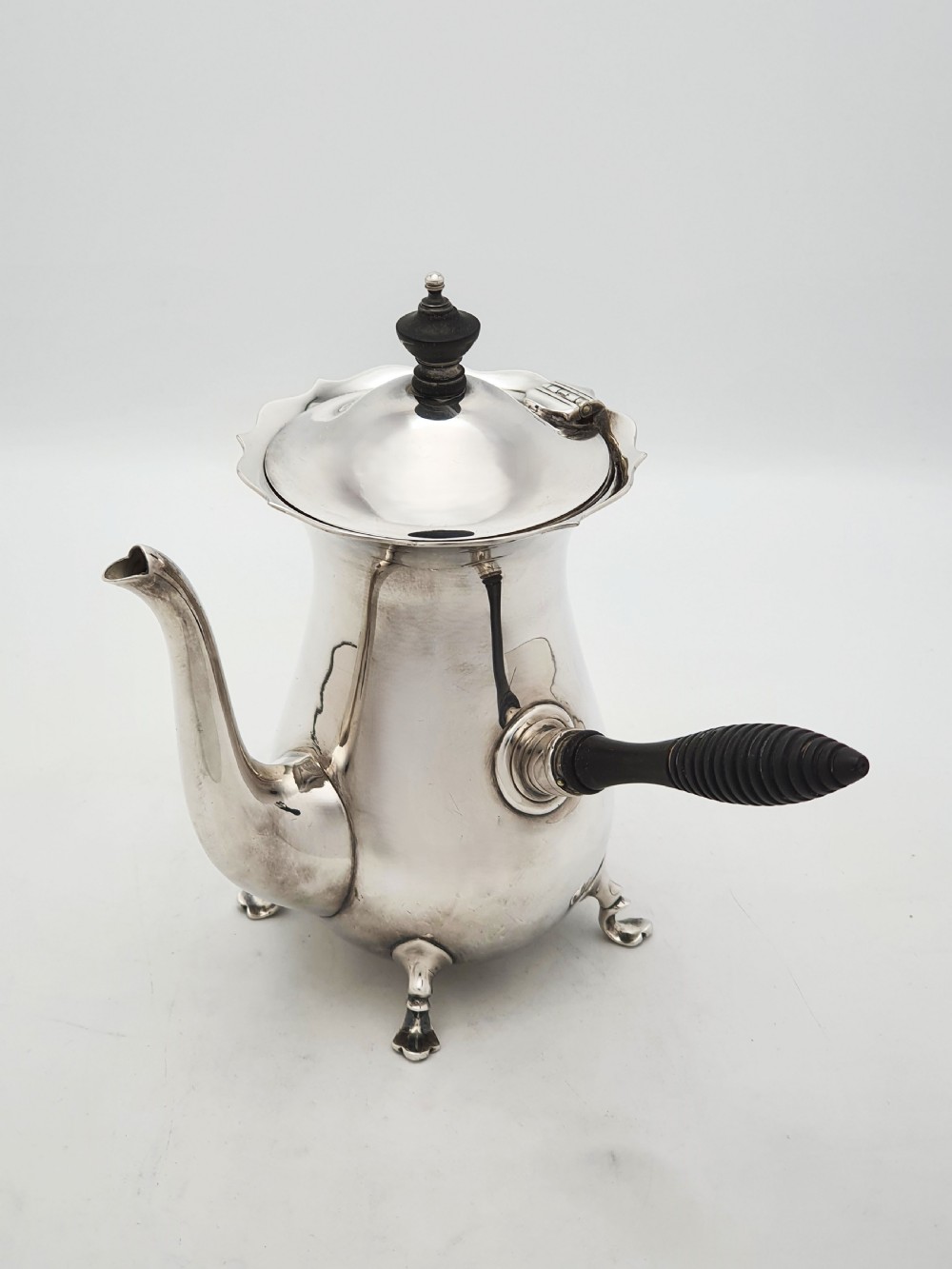 A pair of Edwardian silver cafe au lait pots featuring ribbed wooden side handles, scalloped hinged lids, and carved cabriole feet. View IV