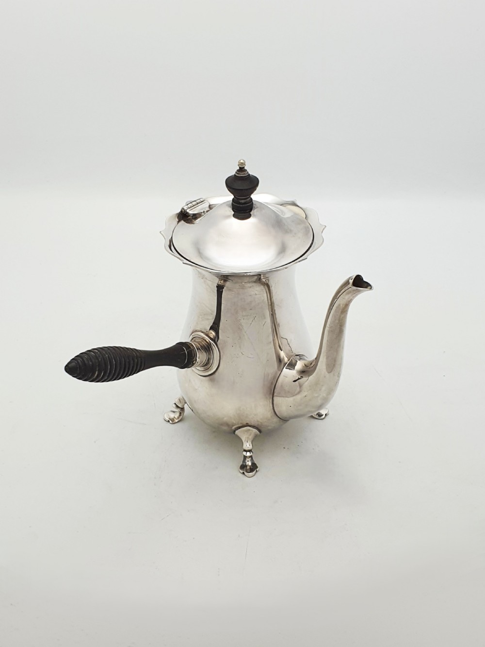 A pair of Edwardian silver cafe au lait pots featuring ribbed wooden side handles, scalloped hinged lids, and carved cabriole feet. View VII