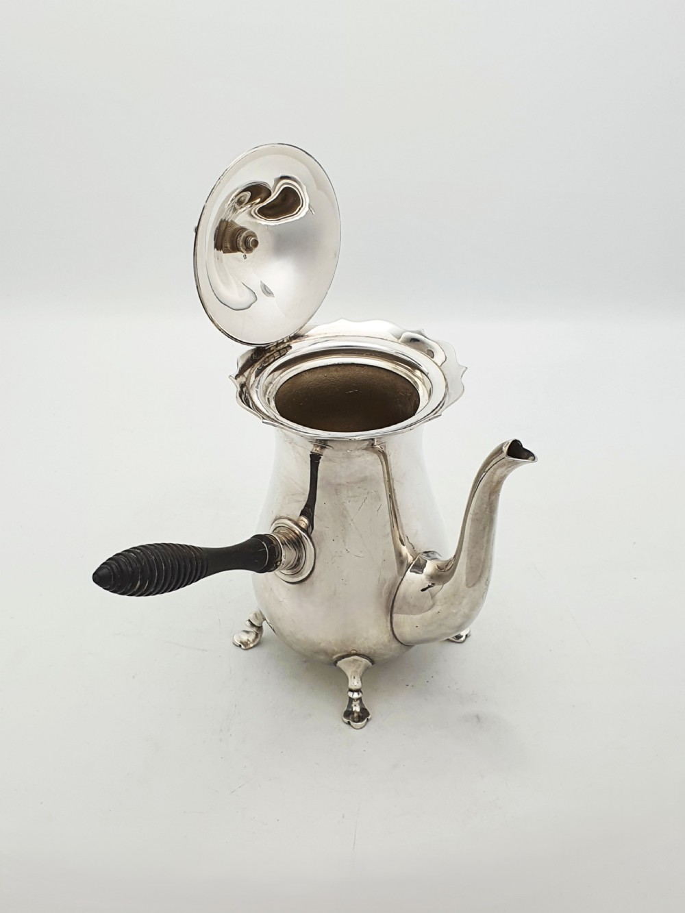 A pair of Edwardian silver cafe au lait pots featuring ribbed wooden side handles, scalloped hinged lids, and carved cabriole feet. View VIII
