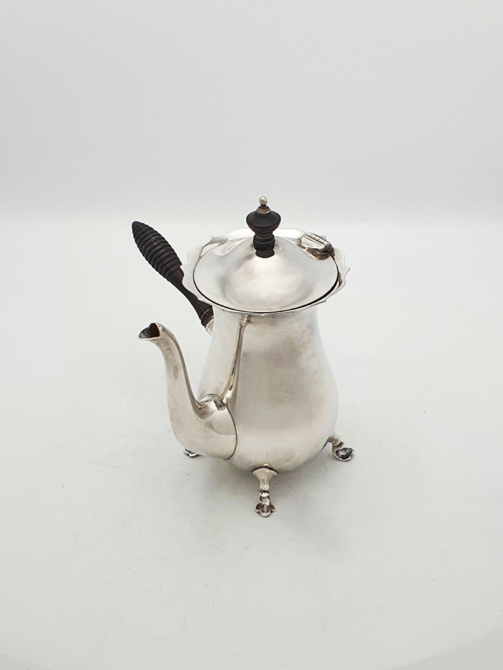 A pair of Edwardian silver cafe au lait pots featuring ribbed wooden side handles, scalloped hinged lids, and carved cabriole feet. View X