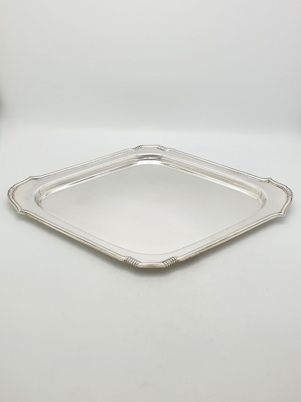 An Art Deco silver-plated serving tray featuring a geometric diamond shape with reeded detailing along the raised rim. View IV