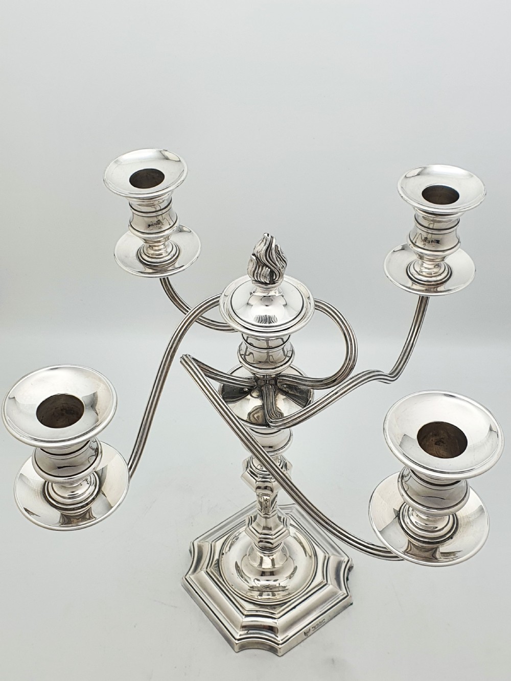 An Edwardian silver-plated five-light candelabrum featuring curved scrolling arms, urn-form sconces, a removable flame finial, and a stepped square base. View II