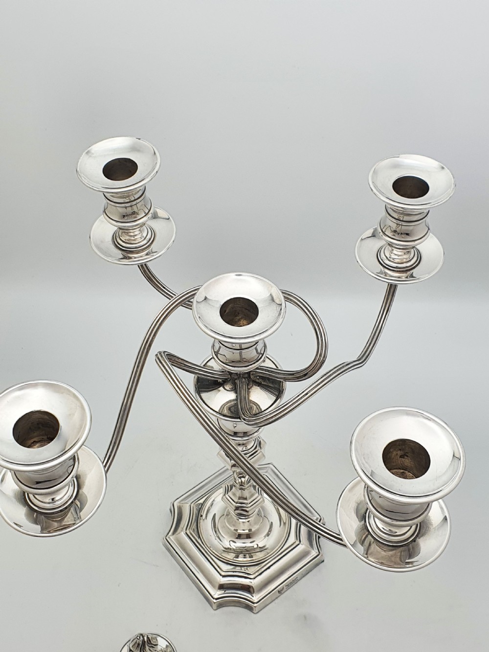An Edwardian silver-plated five-light candelabrum featuring curved scrolling arms, urn-form sconces, a removable flame finial, and a stepped square base. View V