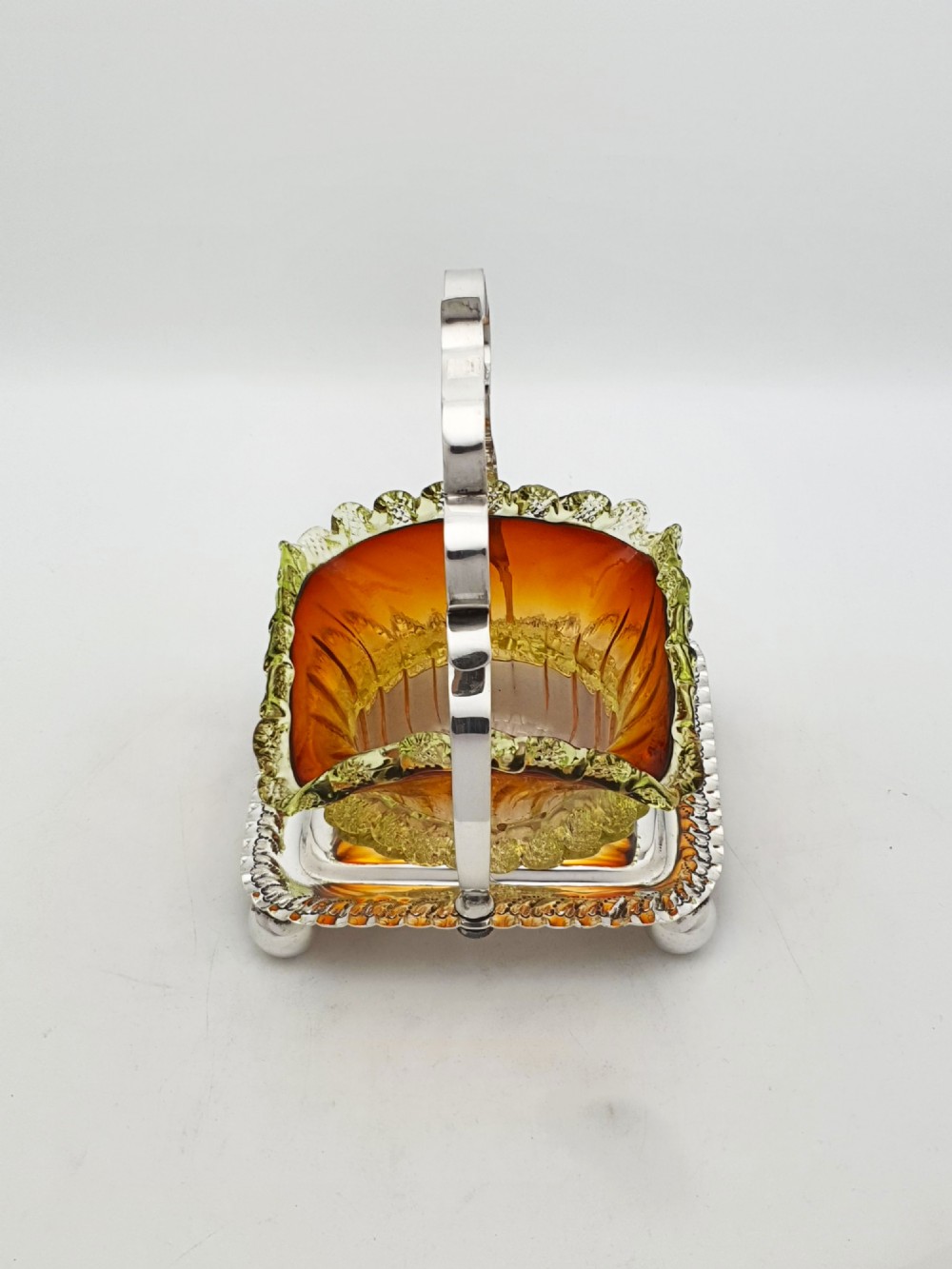 An Edwardian silver-plated stand with a shaped handle and ball feet holding a ruffled amber and yellow glass bonbon dish. View IV
