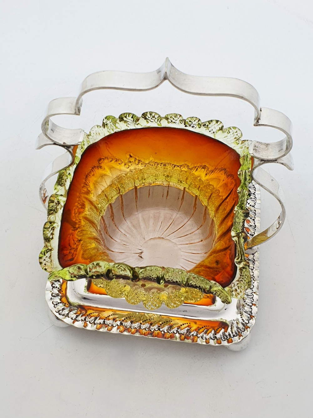 An Edwardian silver-plated stand with a shaped handle and ball feet holding a ruffled amber and yellow glass bonbon dish. View VII