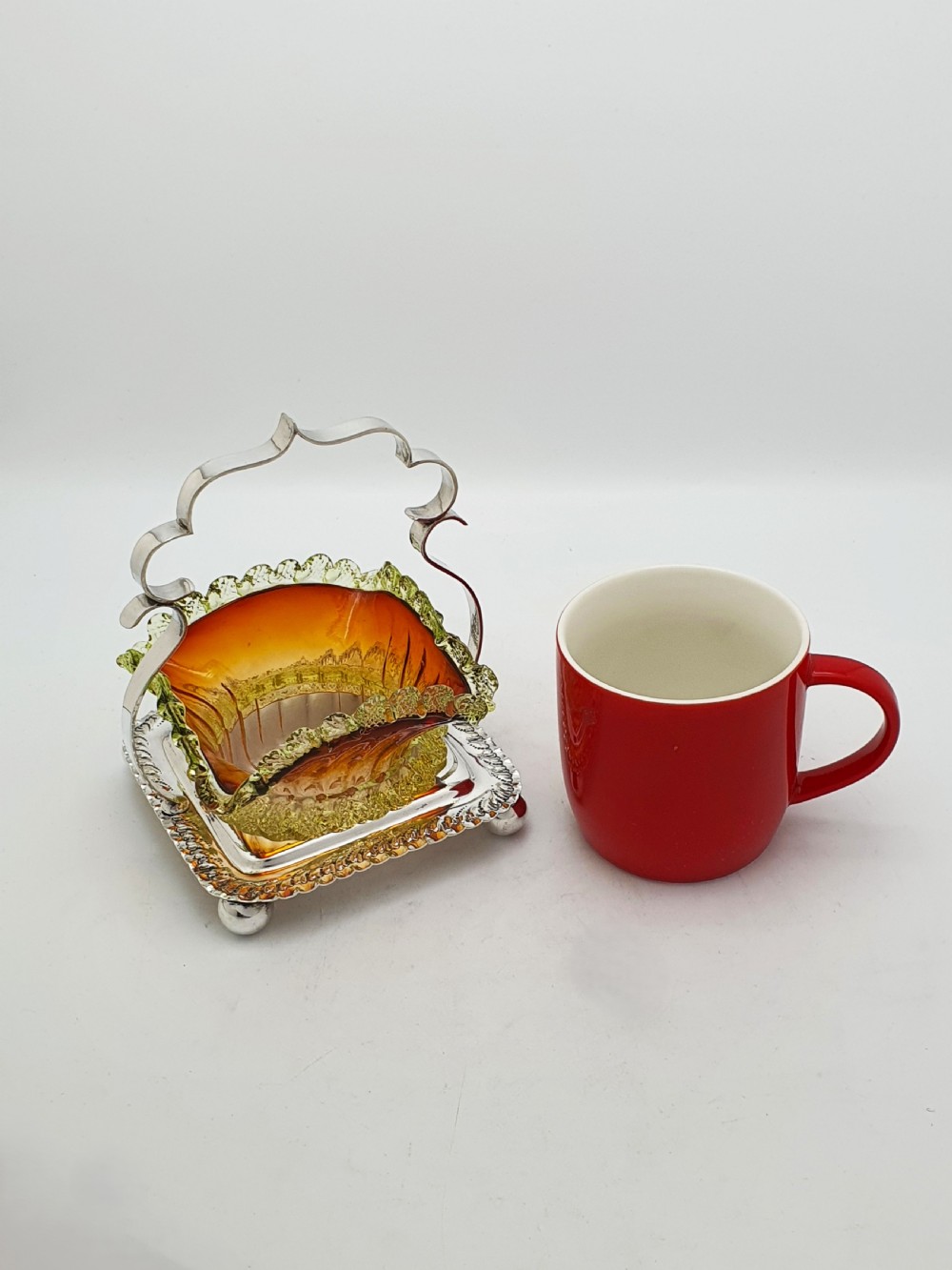 An Edwardian silver-plated stand with a shaped handle and ball feet holding a ruffled amber and yellow glass bonbon dish. View VIII