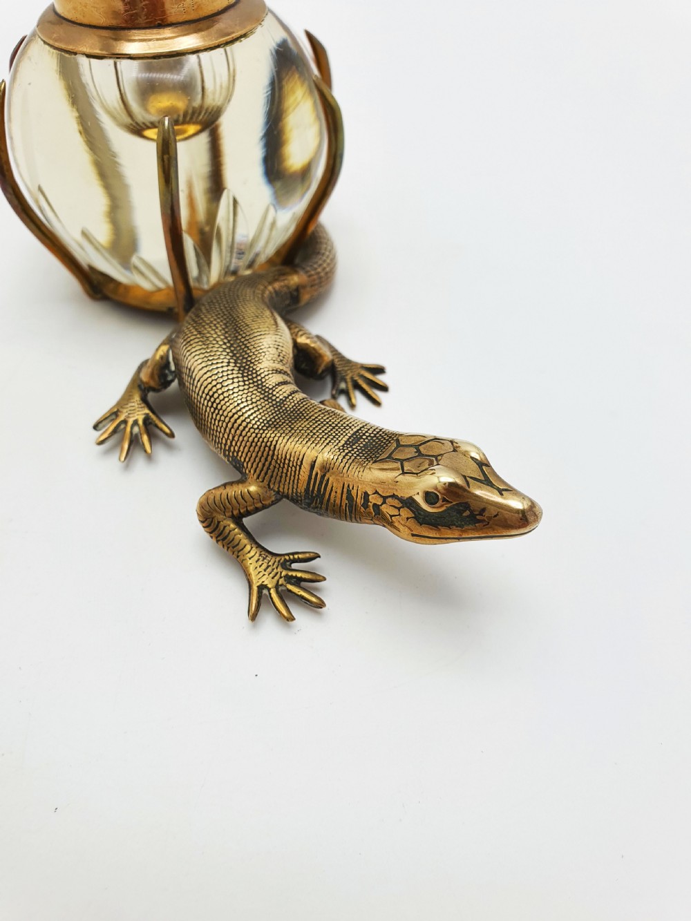 An antique Victorian brass inkstand featuring a cast lizard wrapped around a clear spherical glass inkwell with a crown-shaped hinged lid. View II