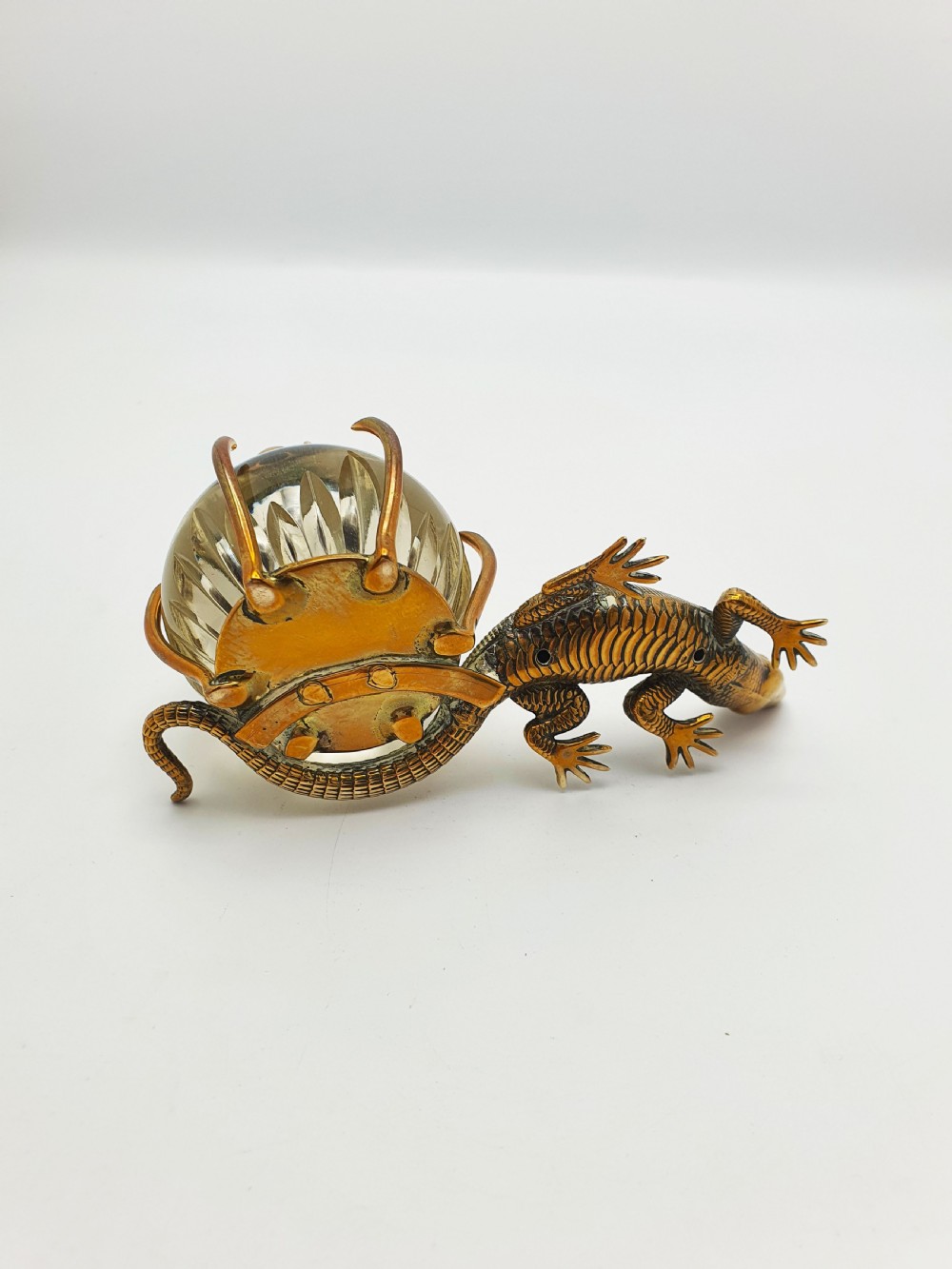 An antique Victorian brass inkstand featuring a cast lizard wrapped around a clear spherical glass inkwell with a crown-shaped hinged lid. View V