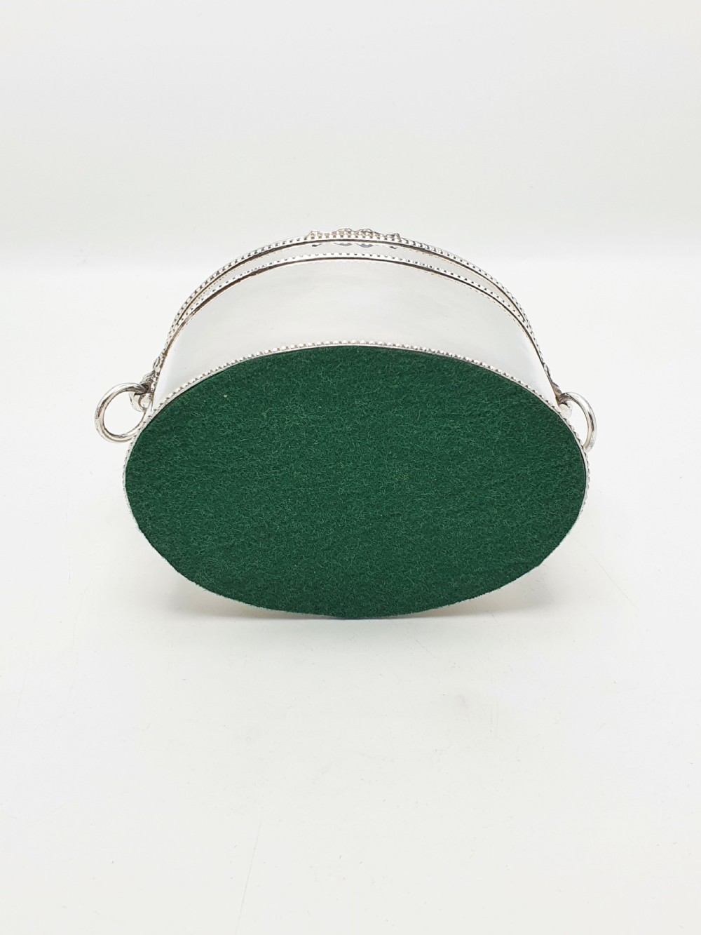 An oval silver tea caddy featuring lion mask ring handles on the sides, a hinged lid with beaded edging, and a front clip holding a small silver caddy spoon. View X