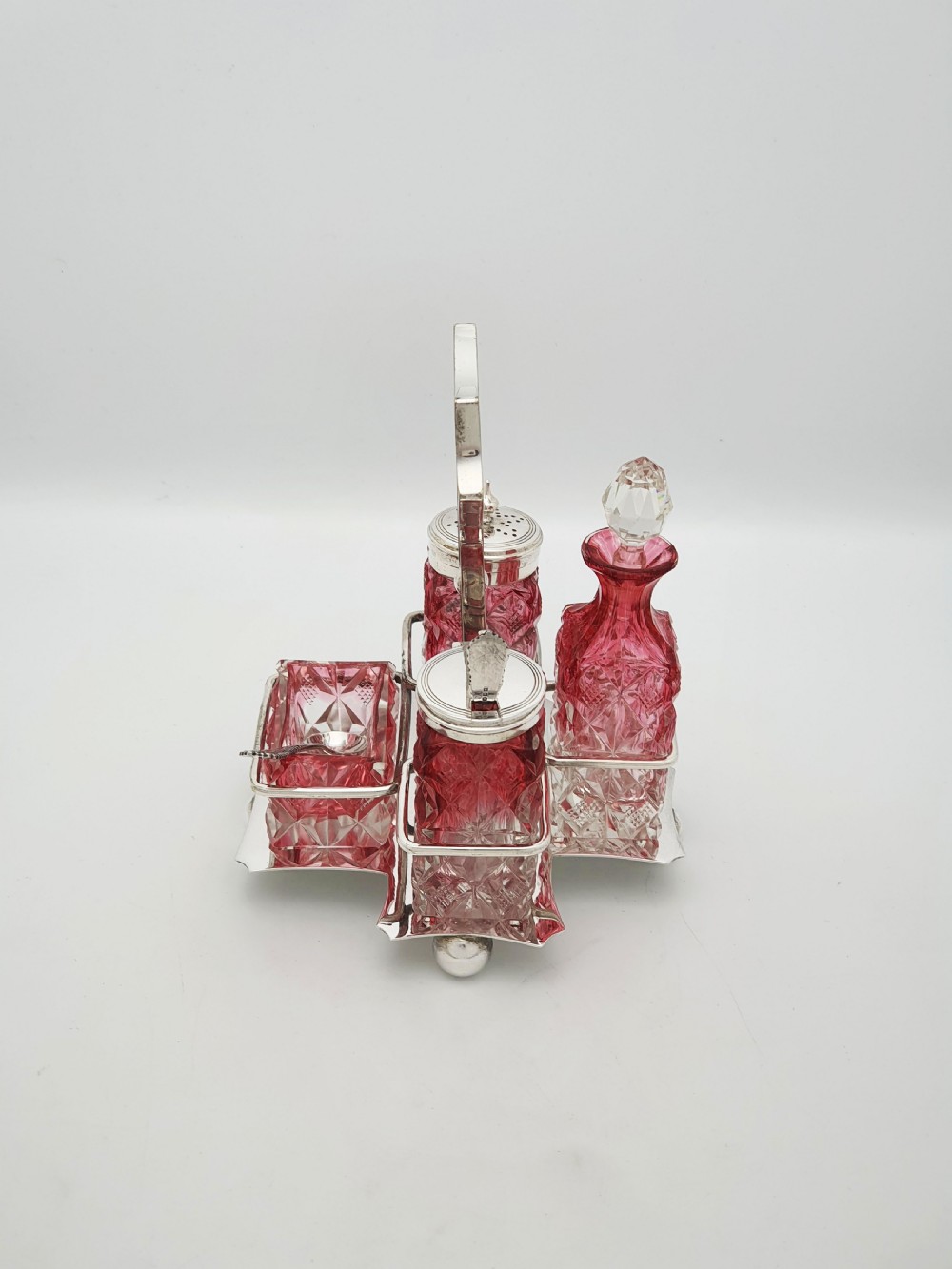 An Edwardian silver-plated stand holding four diamond-cut cranberry flashed glass condiment bottles and jars. View III