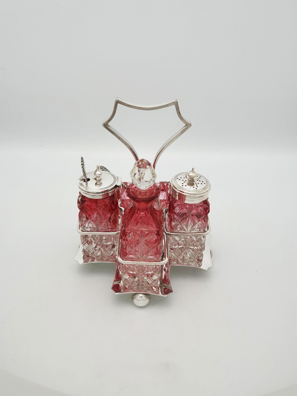 An Edwardian silver-plated stand holding four diamond-cut cranberry flashed glass condiment bottles and jars. View IV