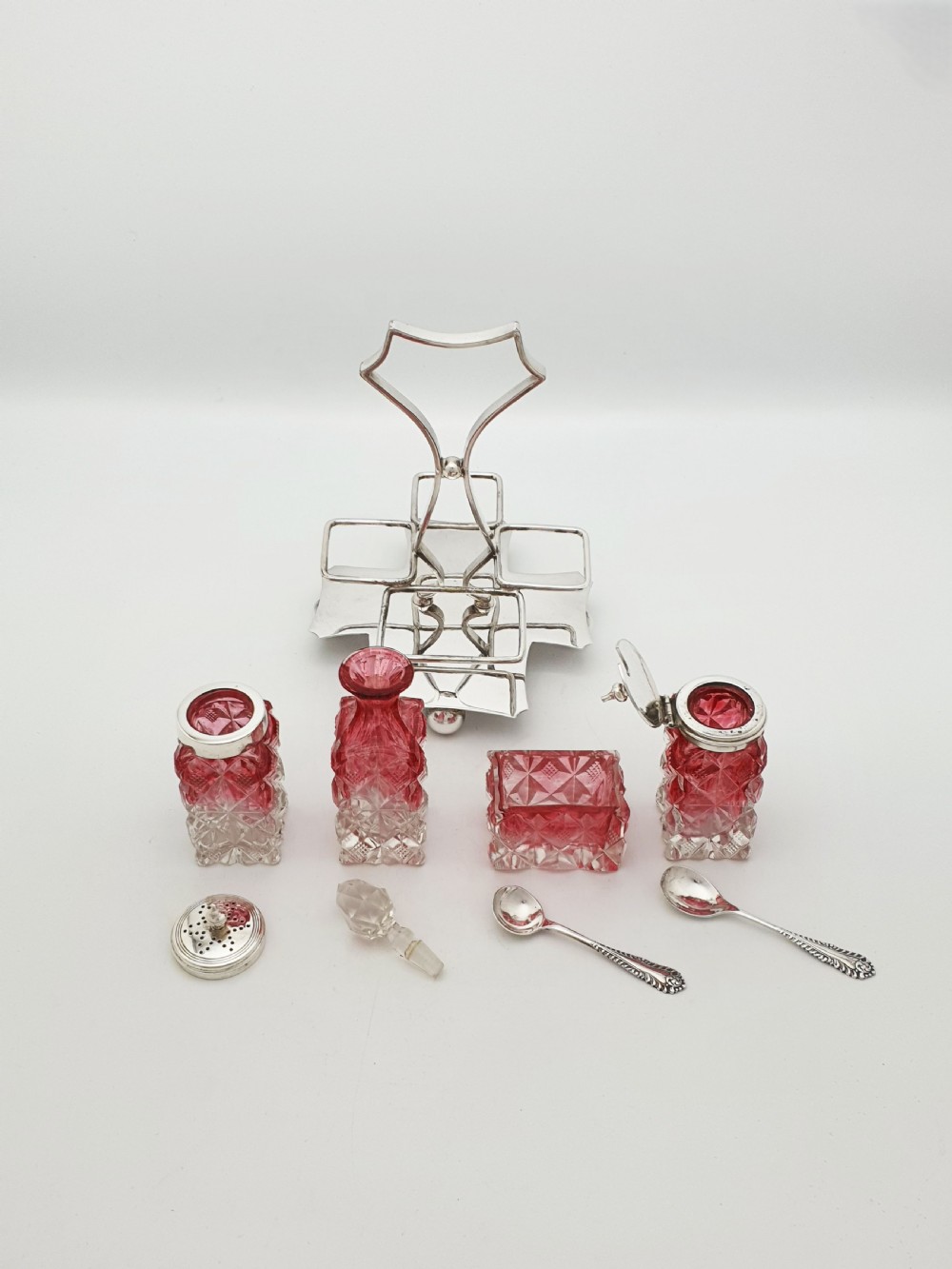 An Edwardian silver-plated stand holding four diamond-cut cranberry flashed glass condiment bottles and jars. View V