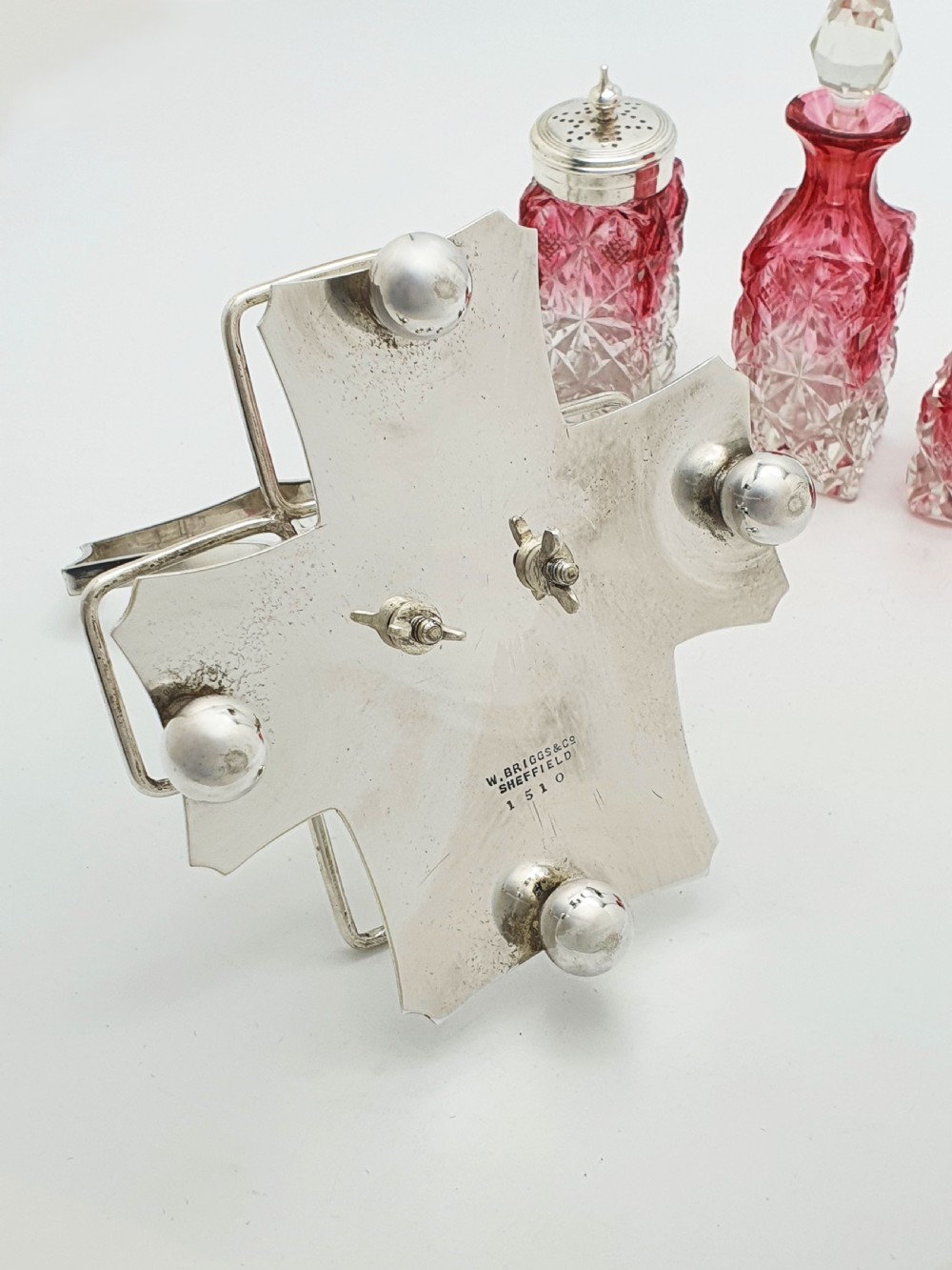An Edwardian silver-plated stand holding four diamond-cut cranberry flashed glass condiment bottles and jars. View VI