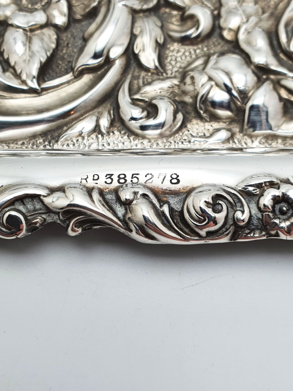 A rectangular sterling silver tray decorated with raised floral repousse patterns and an unengraved central cartouche. View IV