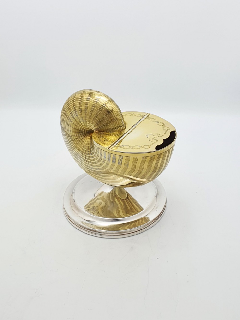 A Victorian silver-plated and gilt metal spoon warmer designed in the form of a nautilus shell on a pedestal base.