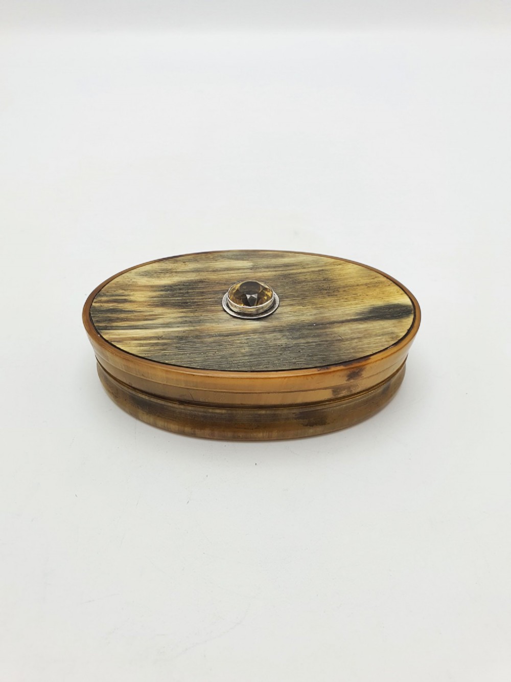 An oval Victorian snuff box made from natural mottled horn featuring a central faceted yellow citrine gem mounted on the lid. View II