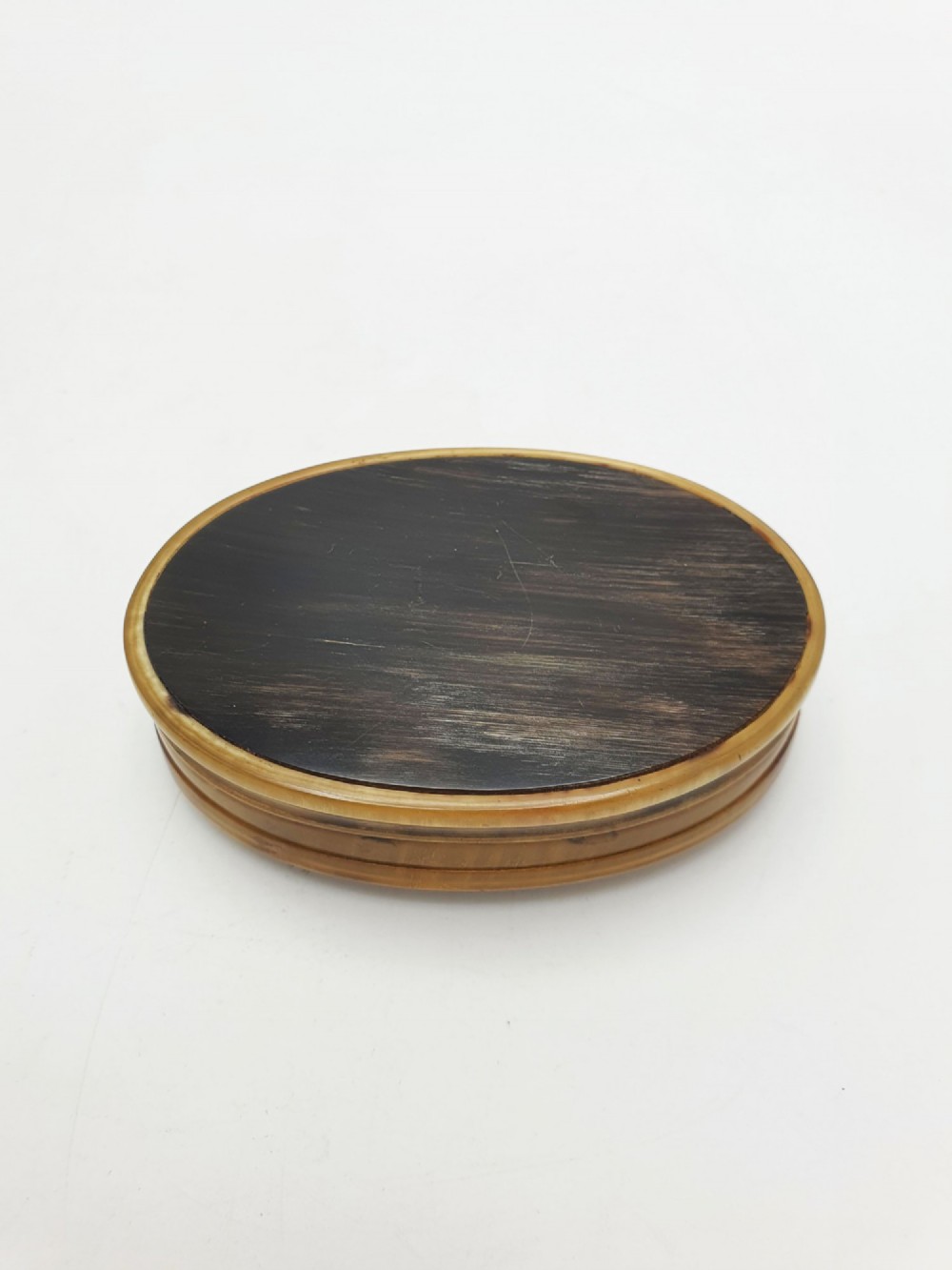 An oval Victorian snuff box made from natural mottled horn featuring a central faceted yellow citrine gem mounted on the lid. View V
