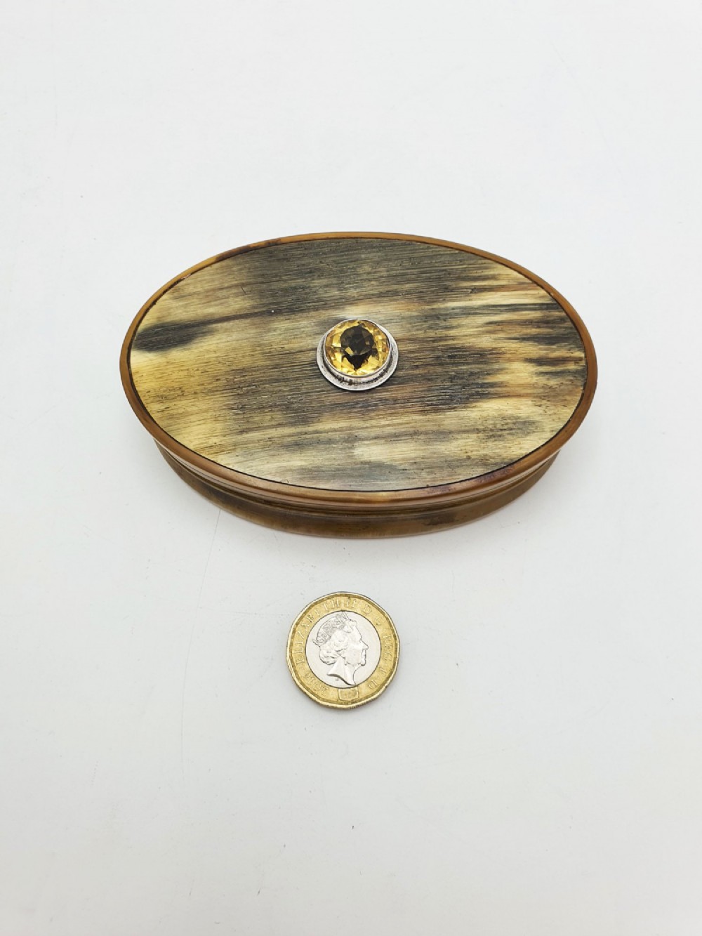 An oval Victorian snuff box made from natural mottled horn featuring a central faceted yellow citrine gem mounted on the lid. View VI