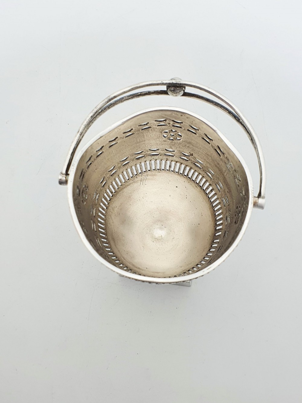 A silver-plated pierced pedestal sugar basket with a swing handle, cobalt blue glass liner, and accompanying sifter spoon. View V