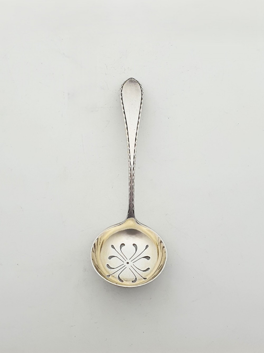A silver-plated pierced pedestal sugar basket with a swing handle, cobalt blue glass liner, and accompanying sifter spoon. View IX