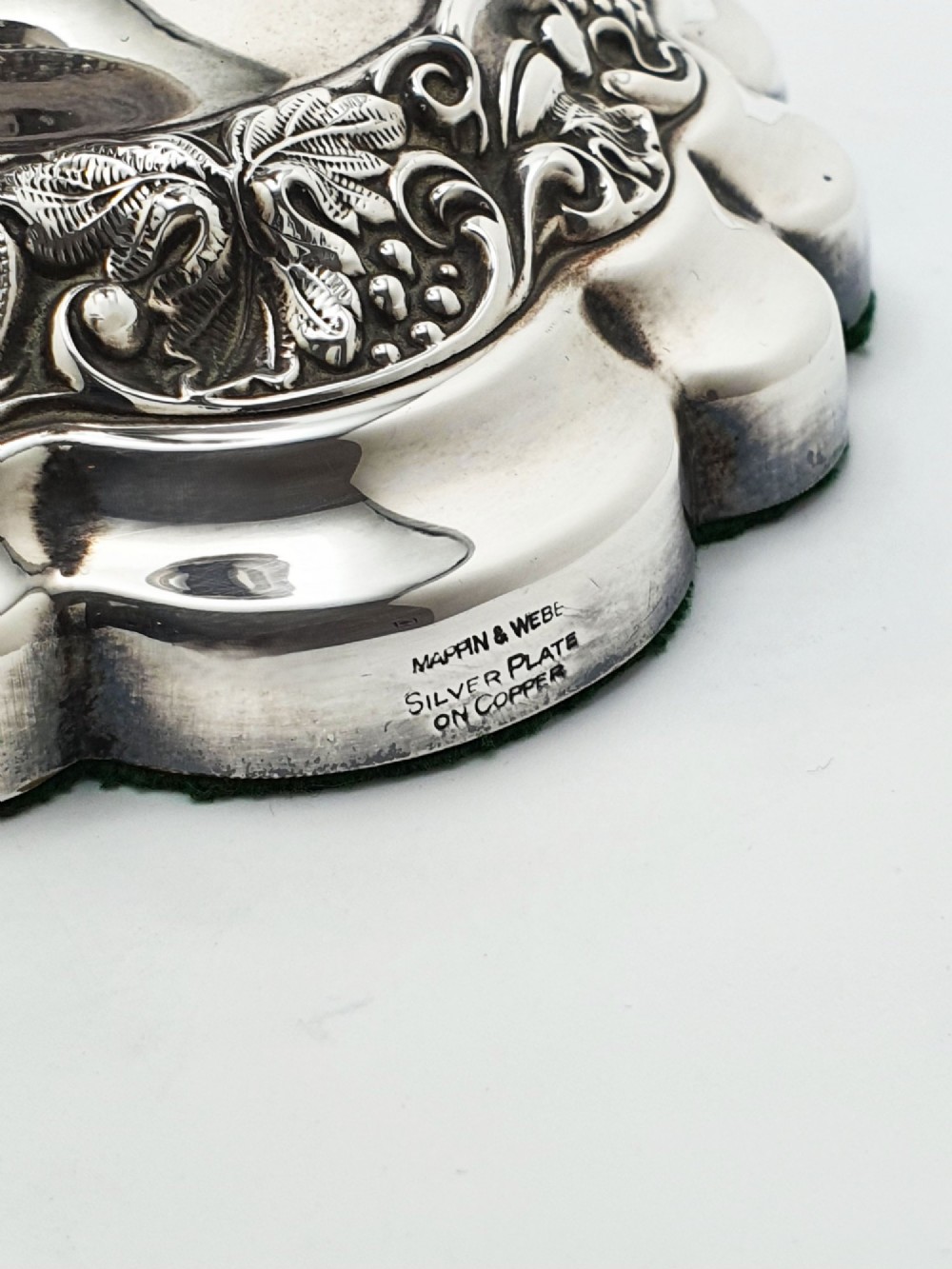 A pair of polished silver-plated candlesticks featuring ornate foliate repousse borders on scalloped bases. View VI