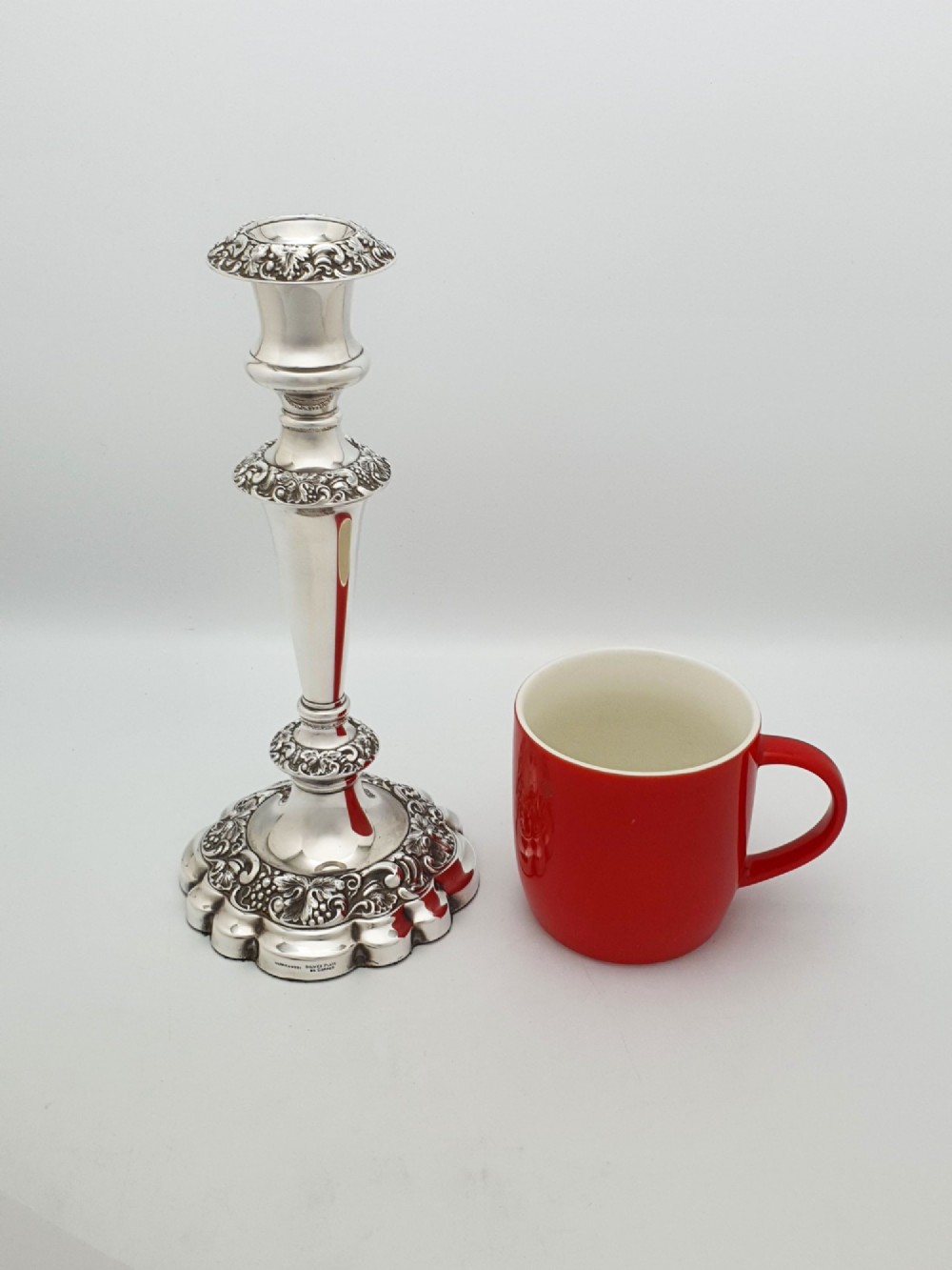 A pair of polished silver-plated candlesticks featuring ornate foliate repousse borders on scalloped bases. View VIII