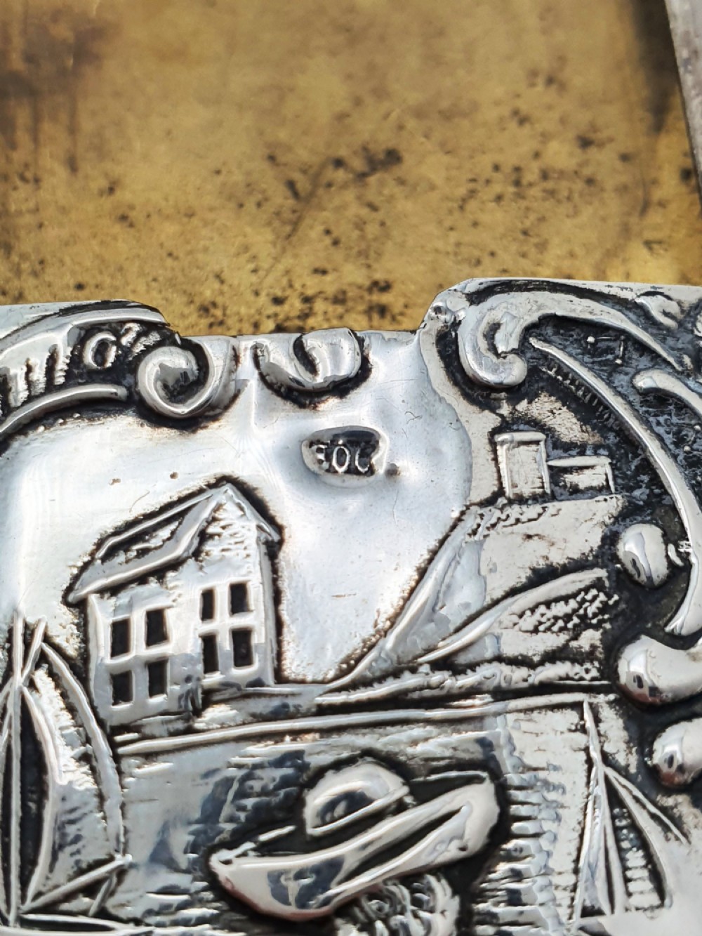 A rectangular silver vesta case with detailed embossed scrollwork around a scenic relief of a figure by water, featuring a sliding gilt interior compartment. View IV