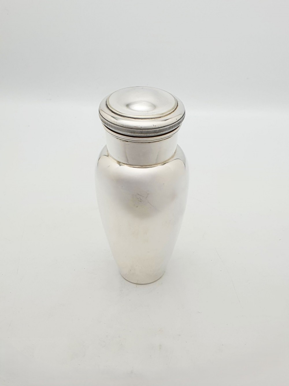 A silver-plated Art Deco bachelor cocktail shaker featuring a baluster body, milled collar, and a domed cap.