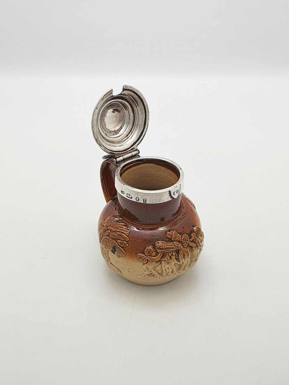 A small salt-glazed brown and beige stoneware jug featuring relief motifs and a hallmarked sterling silver hinged lid and collar. View III