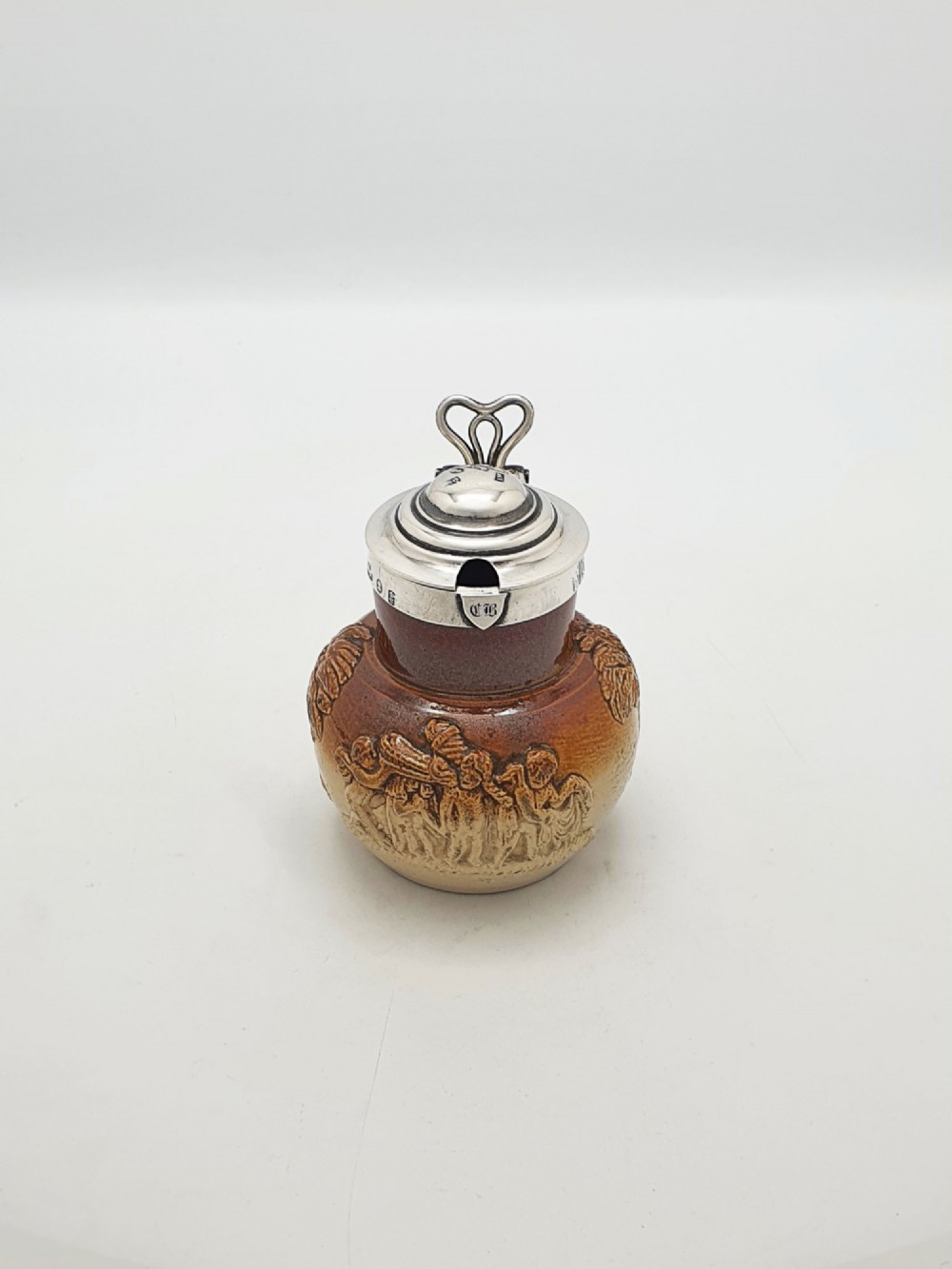 A small salt-glazed brown and beige stoneware jug featuring relief motifs and a hallmarked sterling silver hinged lid and collar. View IV
