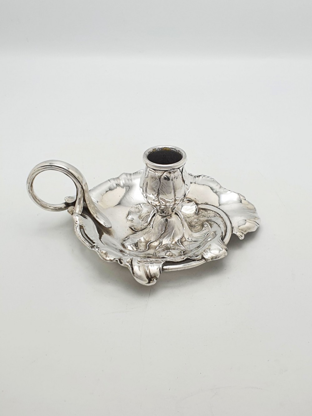An Art Nouveau silver-plated chamberstick featuring a leaf-form tray base, organic sconce nozzle, and a looped handle.