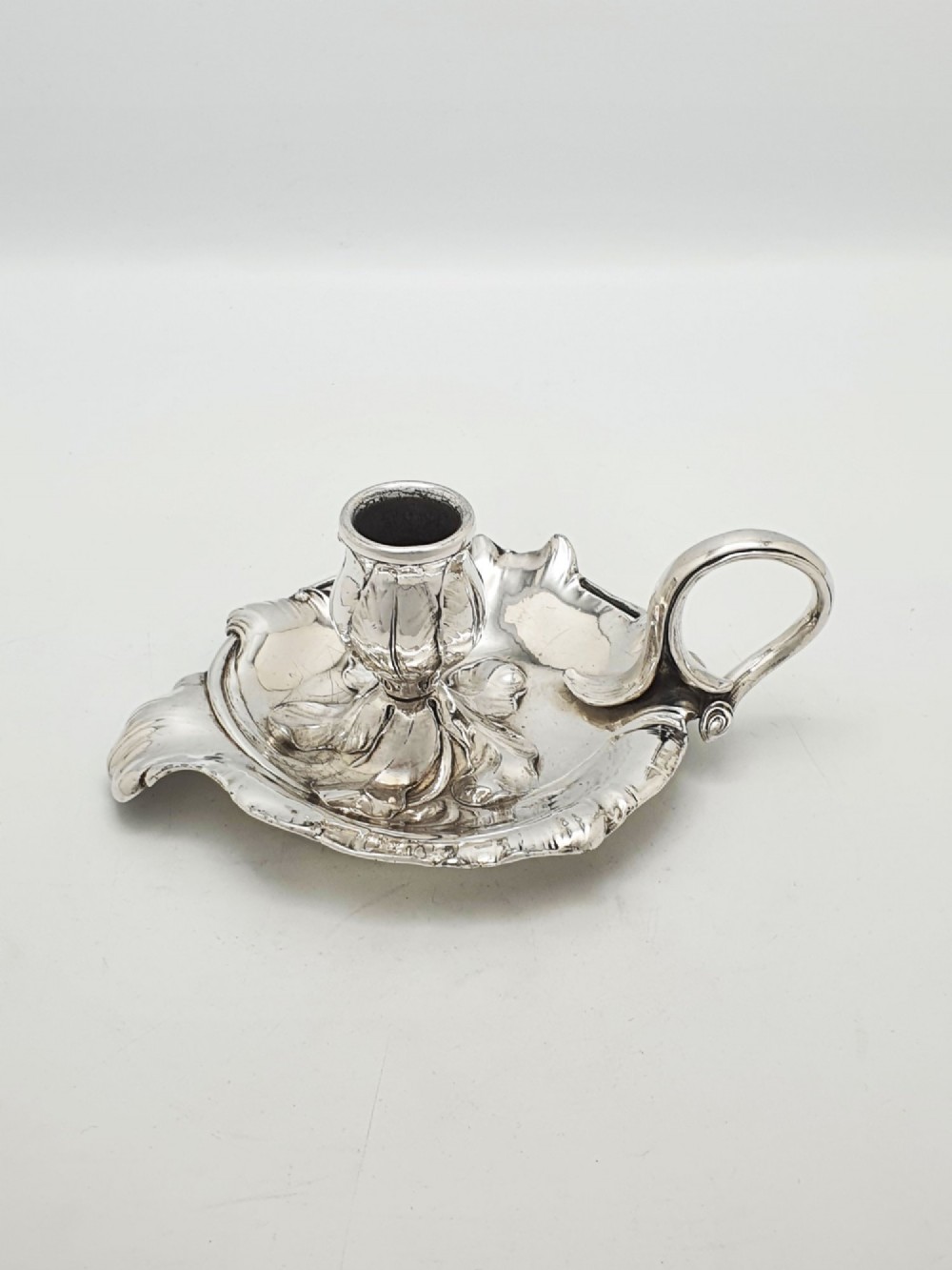 An Art Nouveau silver-plated chamberstick featuring a leaf-form tray base, organic sconce nozzle, and a looped handle. View V
