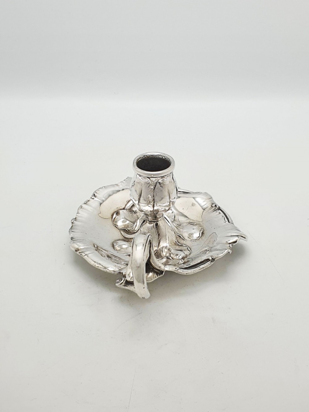 An Art Nouveau silver-plated chamberstick featuring a leaf-form tray base, organic sconce nozzle, and a looped handle. View VI